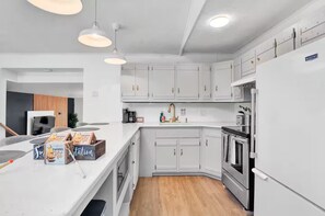 A modern kitchen with white cabinetry, a built-in oven, and a refrigerator. - Secluded Poconos Modern Cabin - Hot Tub, Game Room, Pools & Lake! (Big Bass Lake)