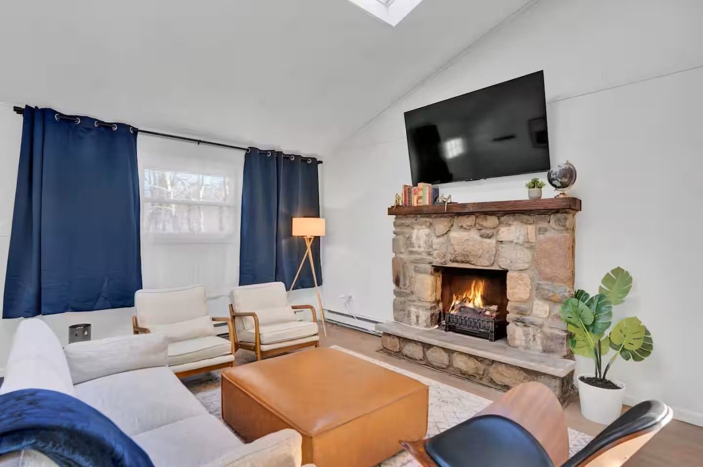 A living room with a stone fireplace, a flat-screen TV, and a sofa.