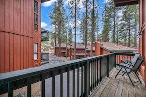 A wooden deck with a railing, overlooking a parking area and buildings with multiple stories. - Steps to Heavenly Mountain | Hot Tub & Fireplace (South Lake Tahoe)
