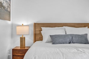 A neatly made bed with white and gray pillows, a wooden headboard, and a bedside table with a lamp. - Steps to Heavenly Mountain | Hot Tub & Fireplace (South Lake Tahoe)
