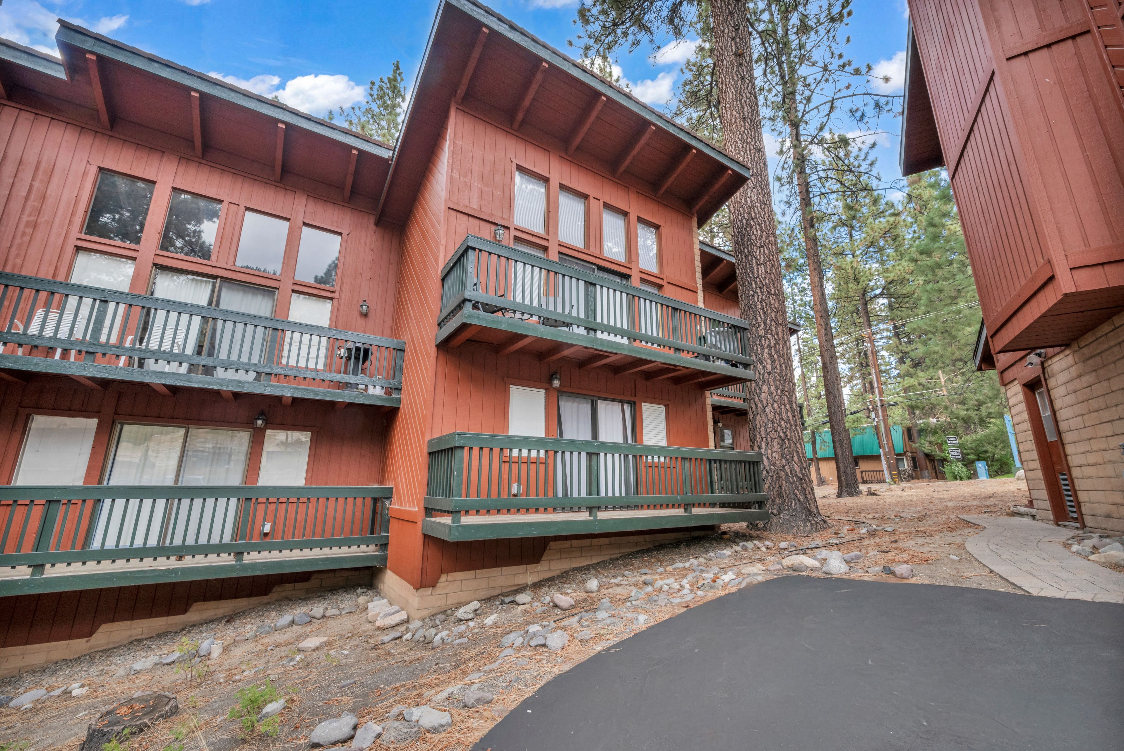 A two-story building with a balcony on each floor, surrounded by trees.