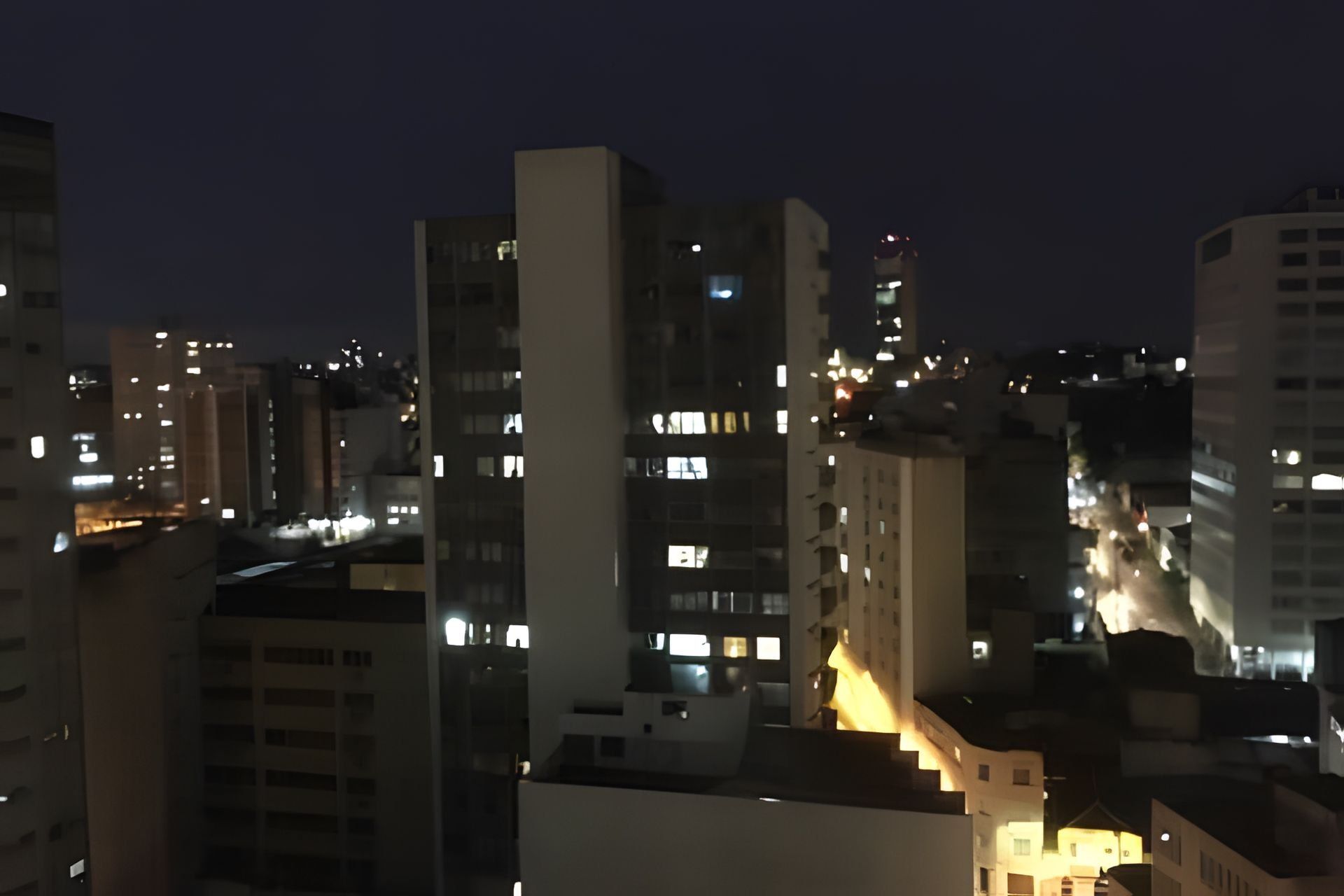 A nighttime cityscape with high-rise buildings, some with illuminated windows.