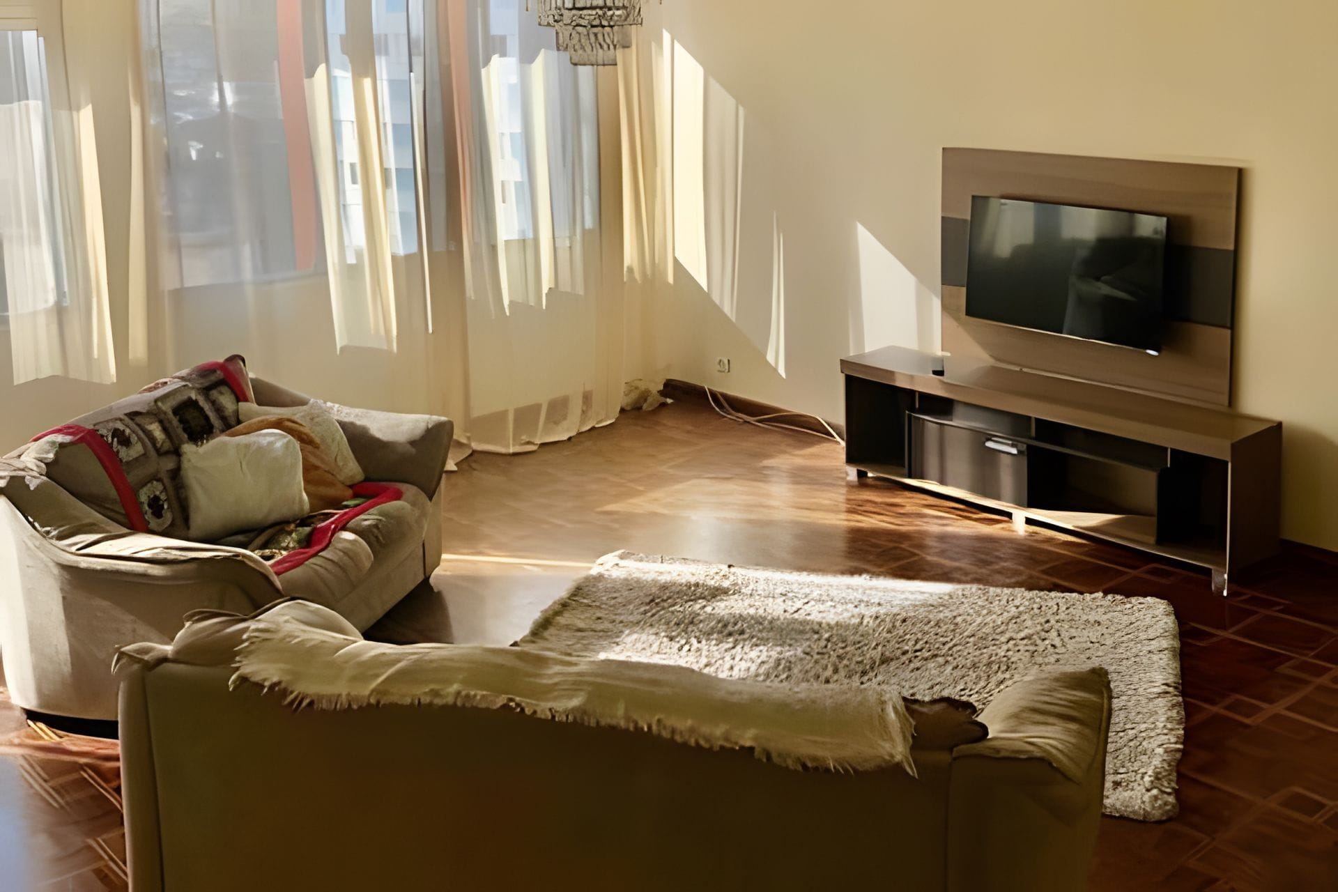 A living room with a sofa, a television, and a rug.