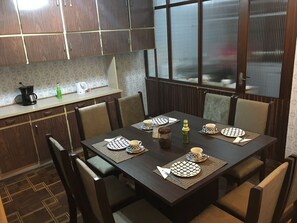 A dining area with a table set for four, chairs, a coffee maker, and a kettle on the counter. - Grande Apartamento no centro de Curitiba (Curitiba)