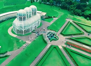 A large, modern building with a unique dome structure, surrounded by well-manicured gardens and pathways. - Grande Apartamento no centro de Curitiba (Curitiba)