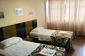 A hotel room with two single beds, a headboard, a window with curtains, and framed pictures on the wall. - Grande Apartamento no centro de Curitiba (Curitiba)