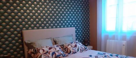 Una cama con una colcha estampada, un cabecero y una pared con un diseño geométrico.