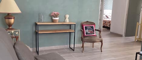 A living room with a sofa, a table with decorative items, a chair, and a lamp.