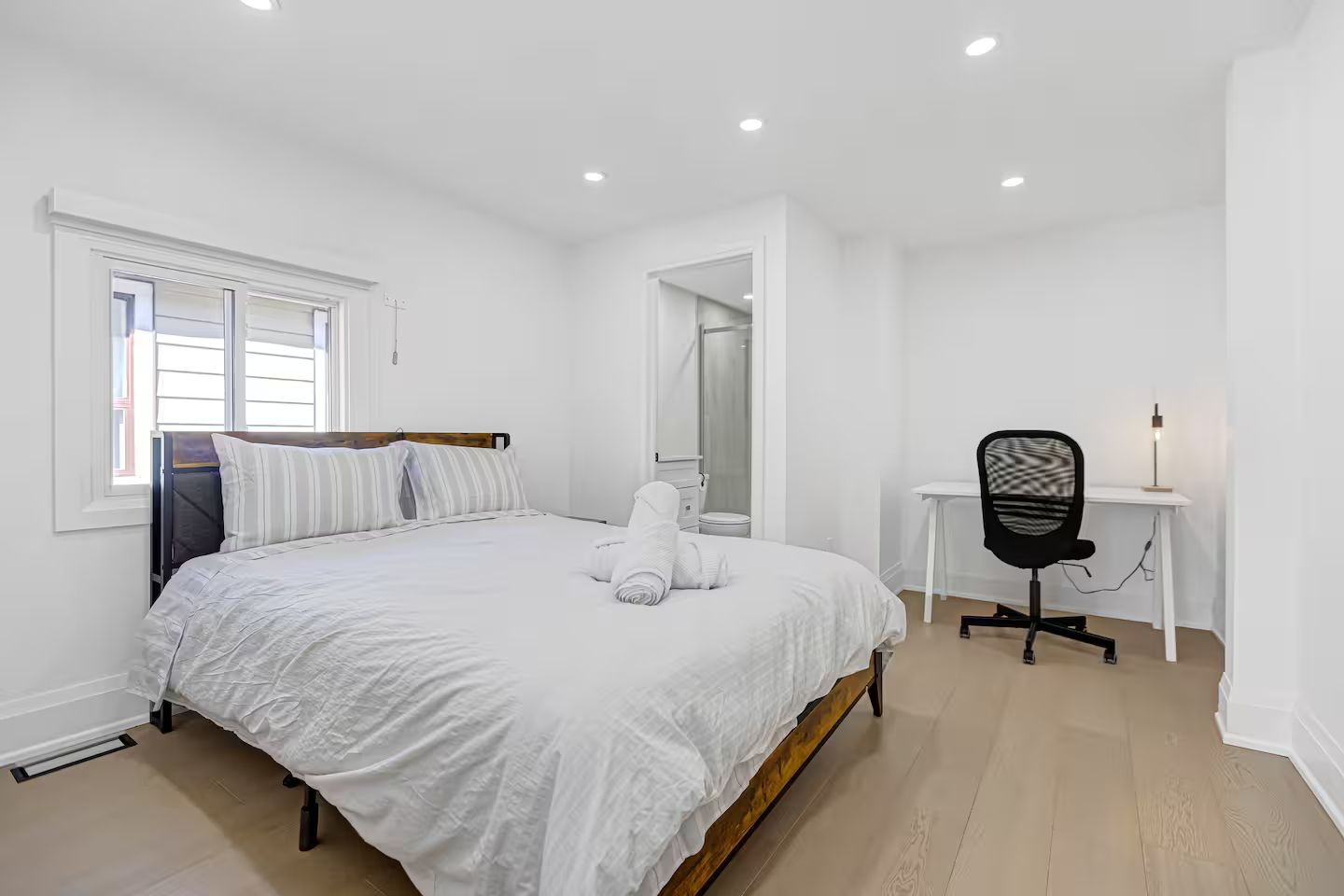 A bedroom with a bed, a desk, and a chair.