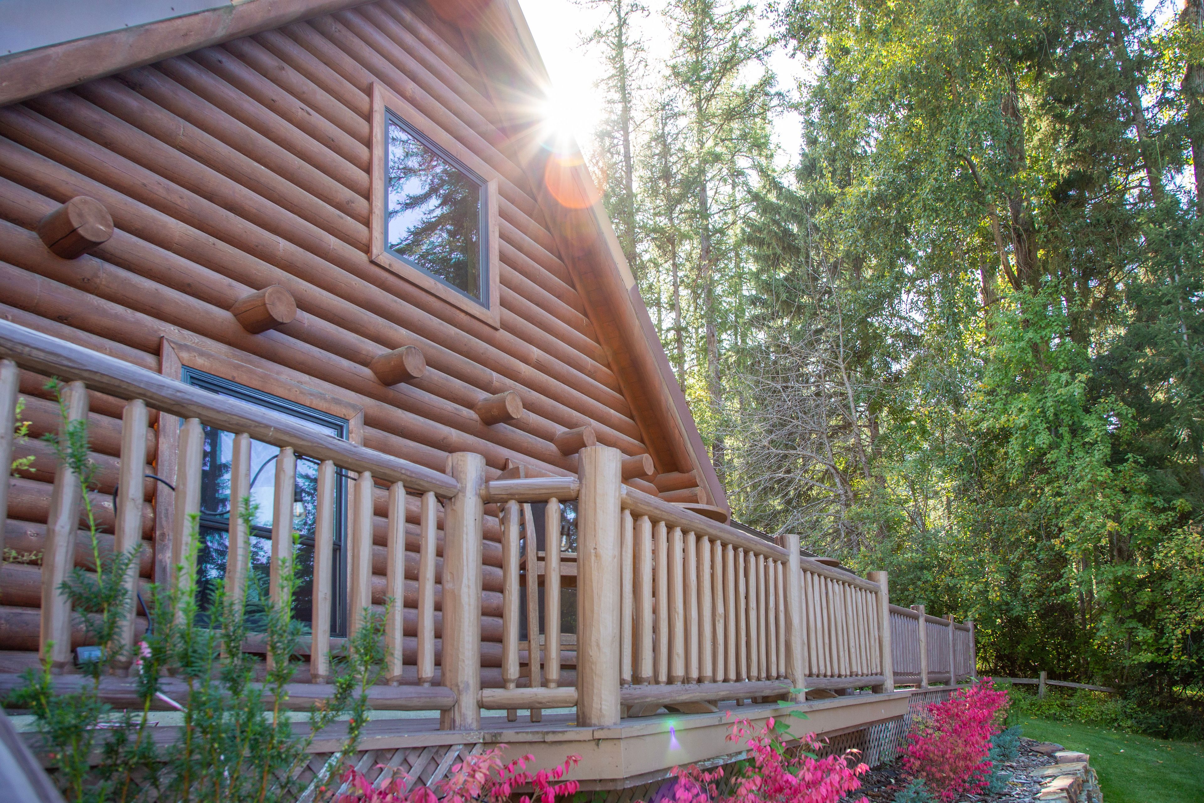 A log cabin with a wooden deck and a view of a forest.