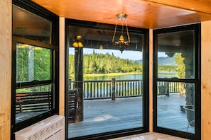 Eine Holzterrasse mit Blick auf einen Wald und einen See.