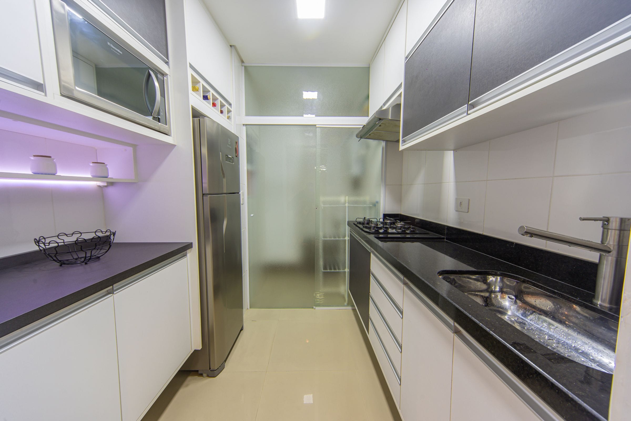 A modern kitchen with stainless steel appliances, a black countertop, and white cabinetry.