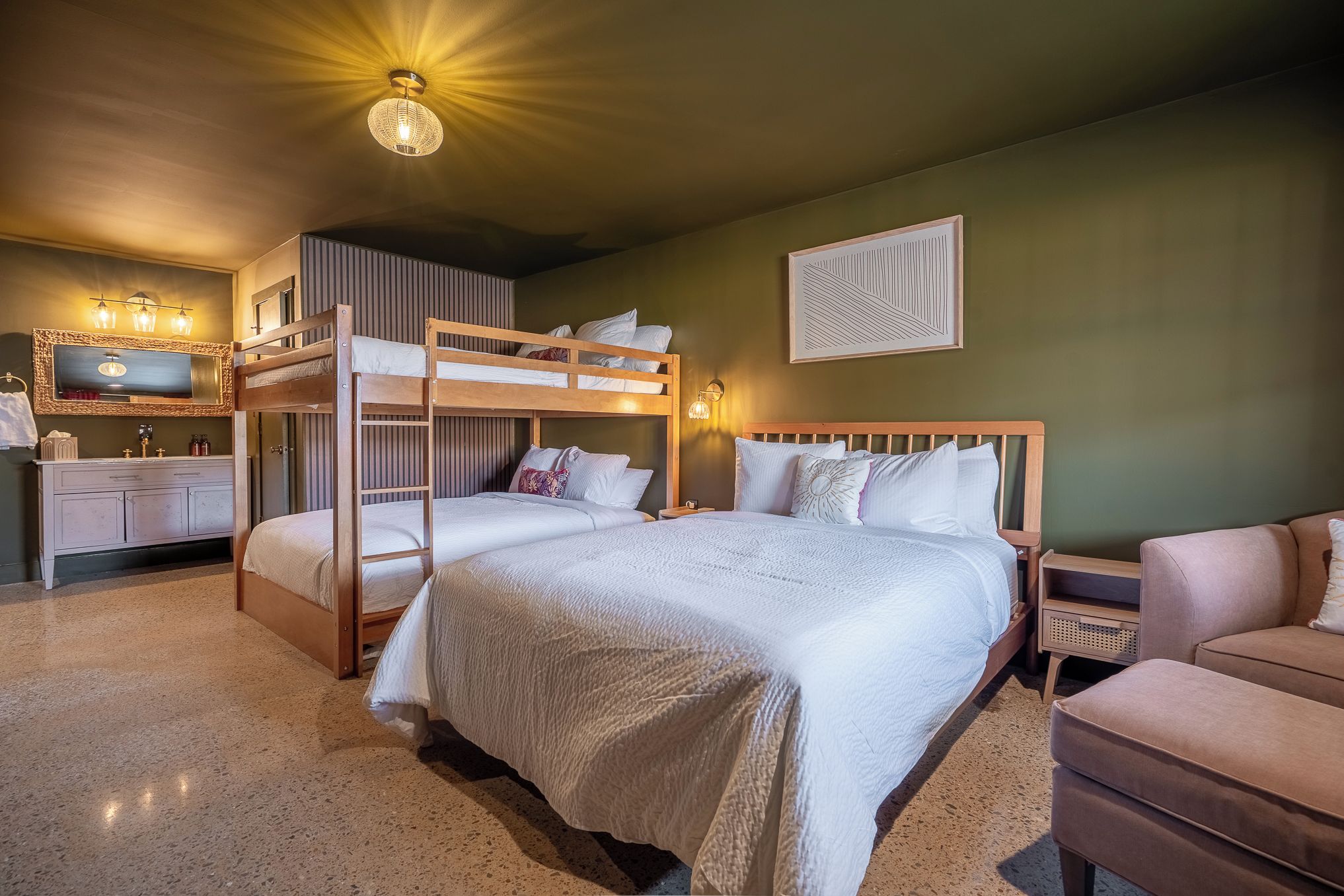Une chambre avec des lits superposés, une coiffeuse avec un miroir et une table de chevet avec une lampe.