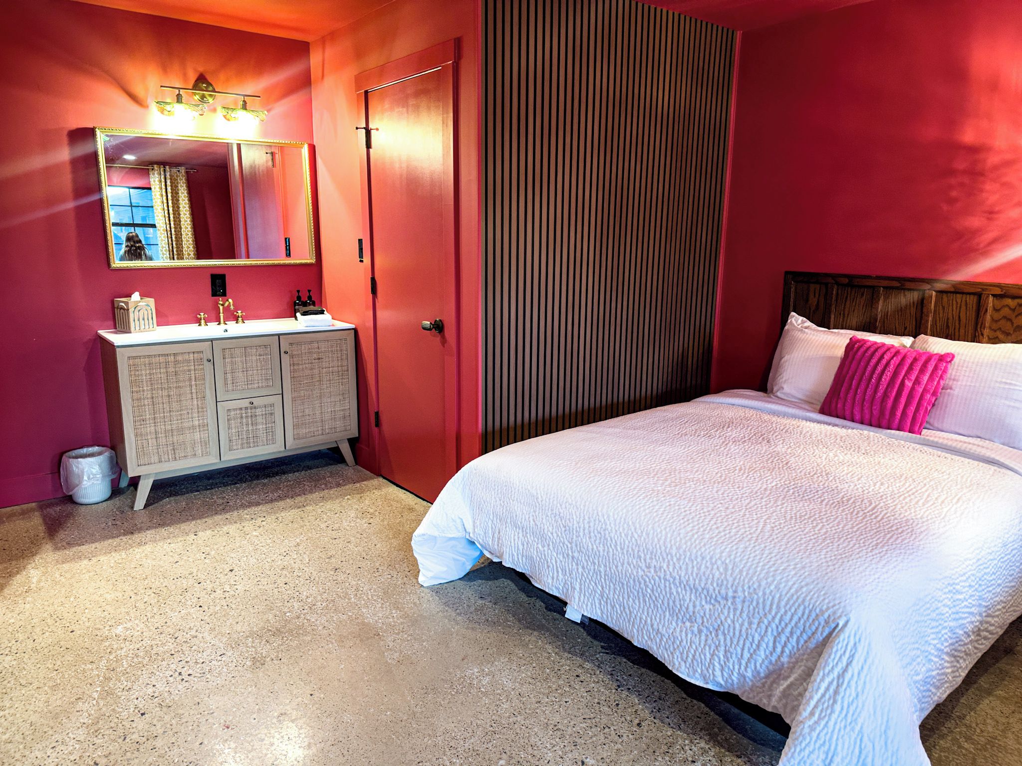 A bedroom with a bed, a dresser, a mirror, and a door.