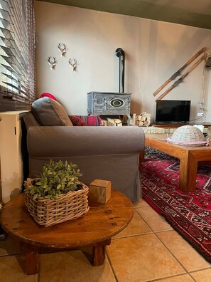 Ein gemütliches Wohnzimmer mit einer Couch, einem Fernseher, einem Kamin und einer Wandverkleidung.