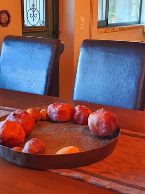 A dining table with a metal tray holding several round objects, possibly food items, and two dark-colored chairs with a wooden table. - Eleni's Guesthouse Country House with Wi-Fi and Mountain Views (Επτάλοφος)