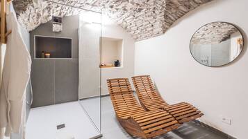 Un bagno moderno con soffitto in pietra, una panca di legno e uno specchio rotondo.