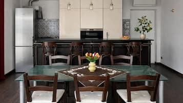 Una cocina moderna con una mesa de vidrio, sillas de madera e iluminación colgante.