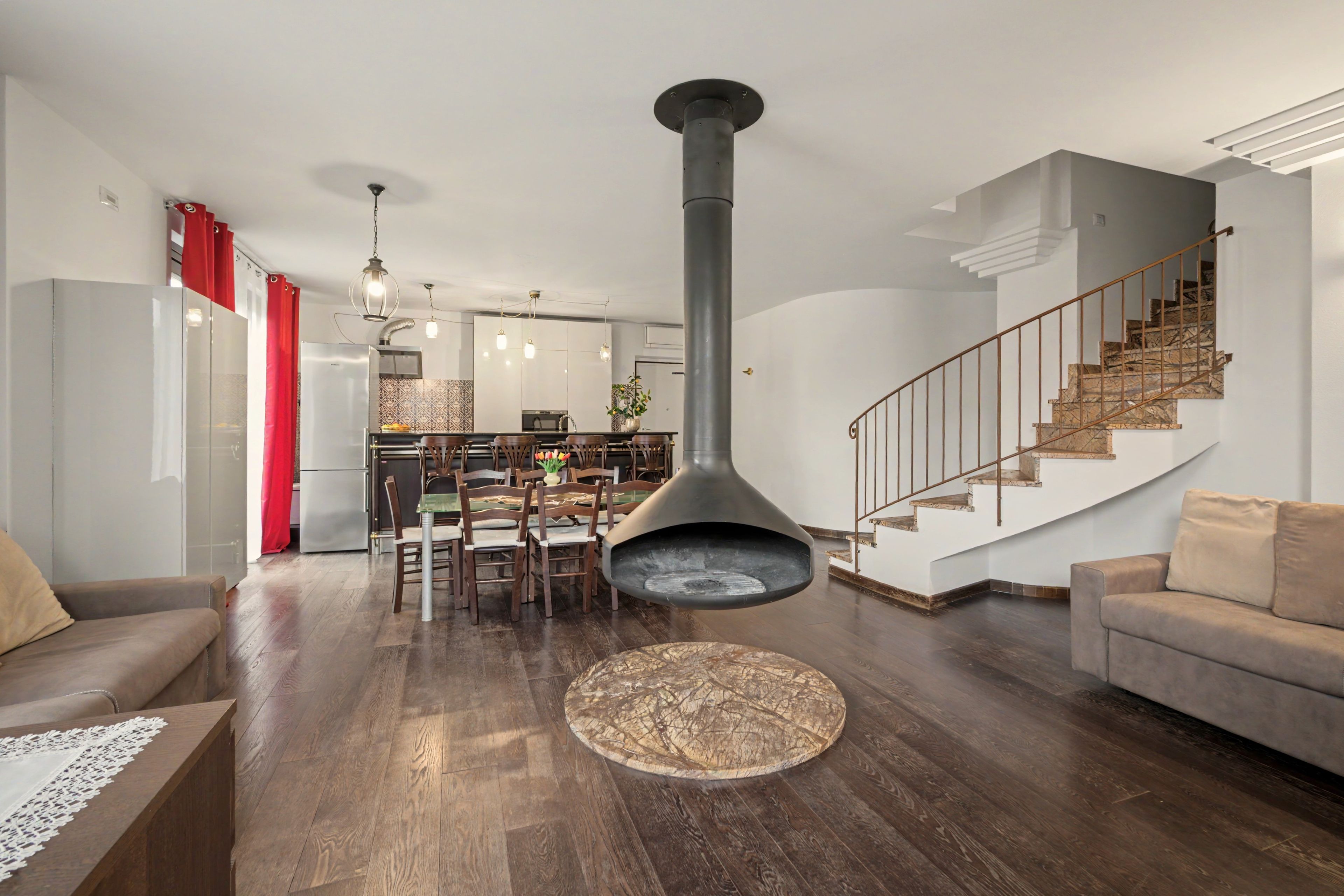 A modern living room with a fireplace, a dining area, and a staircase.