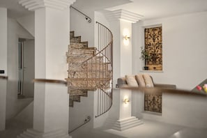 A staircase with a metal railing, a wall-mounted light fixture, and a decorative panel with a plant.