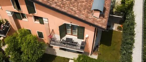 Un immeuble à plusieurs étages, doté d’un toit recouvert de tuiles, d’un balcon agrémenté de mobilier d’extérieur et d’un jardin bien entretenu.