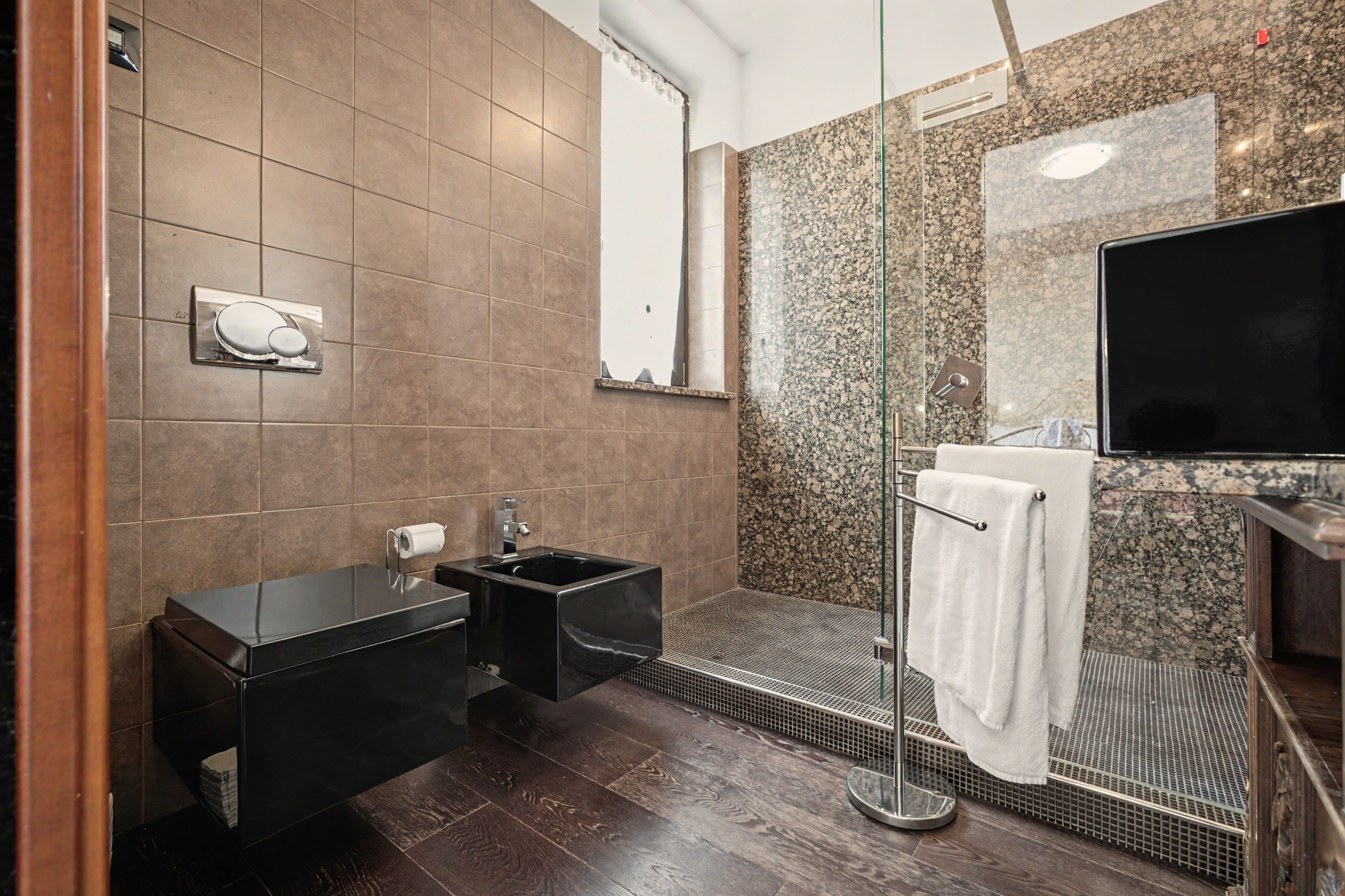 Ein modernes Badezimmer mit einem schwarzen Waschtisch, einer Glasdusche und einem großen Spiegel.