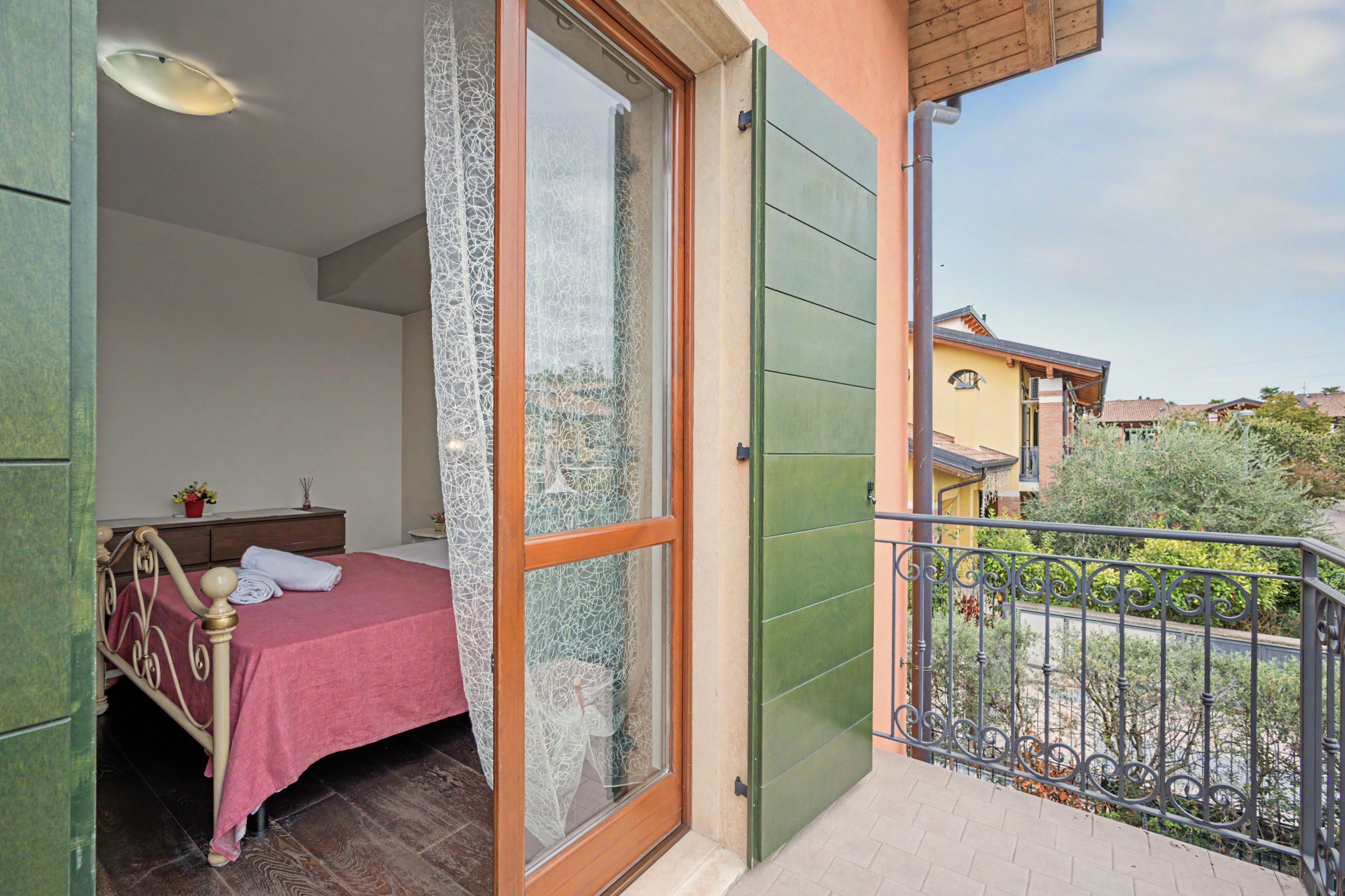 A room with a bed, a nightstand, and a window with a view of the outside.