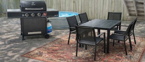 Une terrasse extĂ©rieure Ă©quipĂ©e dâun barbecue, dâune table, de chaises et dâun jacuzzi.