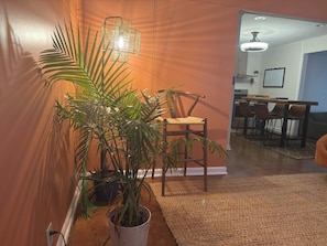 Un pasillo con una planta en maceta, una silla y un comedor al fondo.
