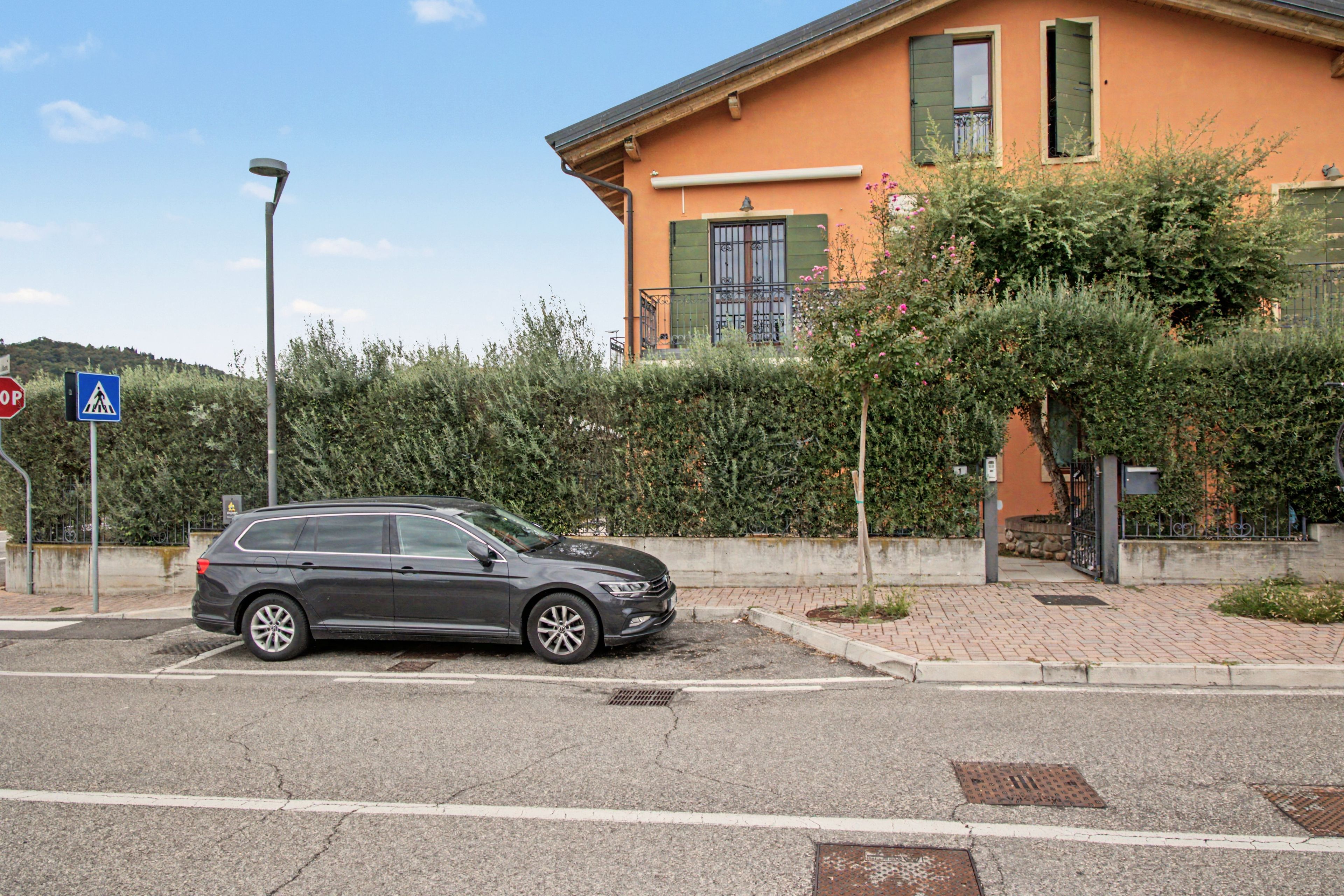 Ein geparktes Auto vor einem Gebäude, in der Nähe ein Fußgängerüberweg.