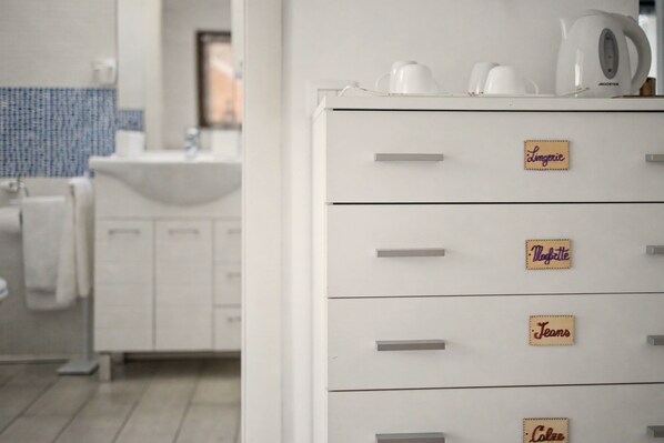 A kitchen with white cabinets and a coffee maker on top. There are labels on the cabinets with names.