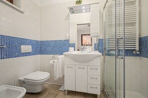 A bathroom with a toilet, bidet, sink, and shower area.