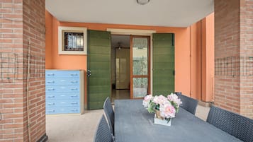Een kamer met een tafel, stoelen, een blauwe kast en een deur naar een andere kamer.