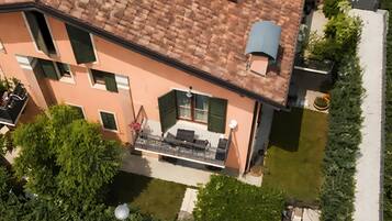 A multi-story building with a tiled roof, a balcony with outdoor furniture, and a well-maintained garden.