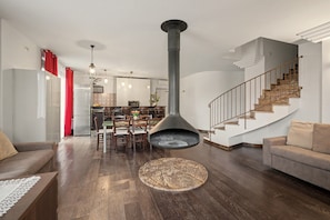 A modern living room with a fireplace, a dining area, and a staircase.