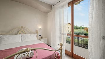 Ein Schlafzimmer mit einem Bett, einem Nachttisch und Blick auf einen Balkon.