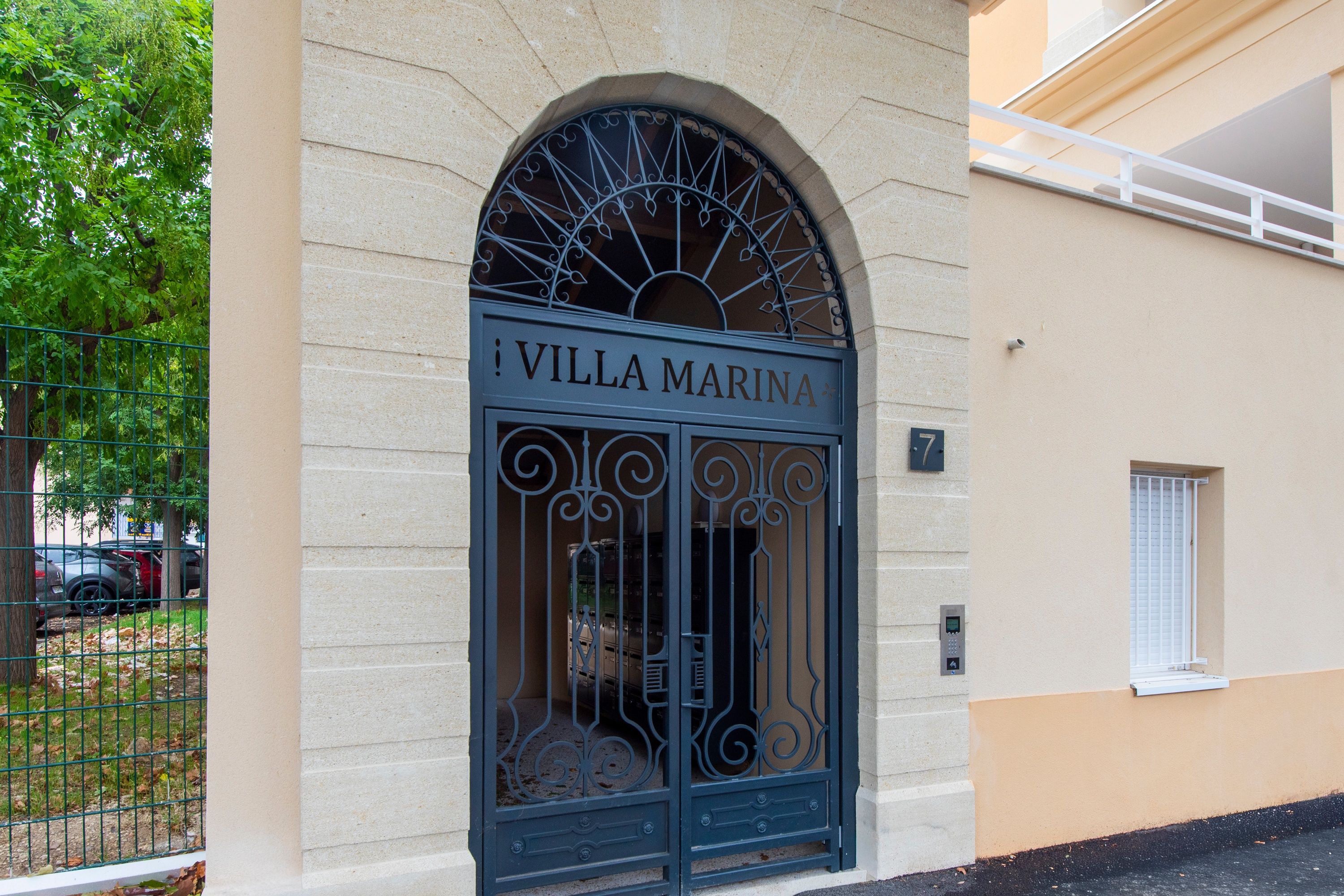 A building entrance with a sign reading 'Villa Marina' and a metal gate.