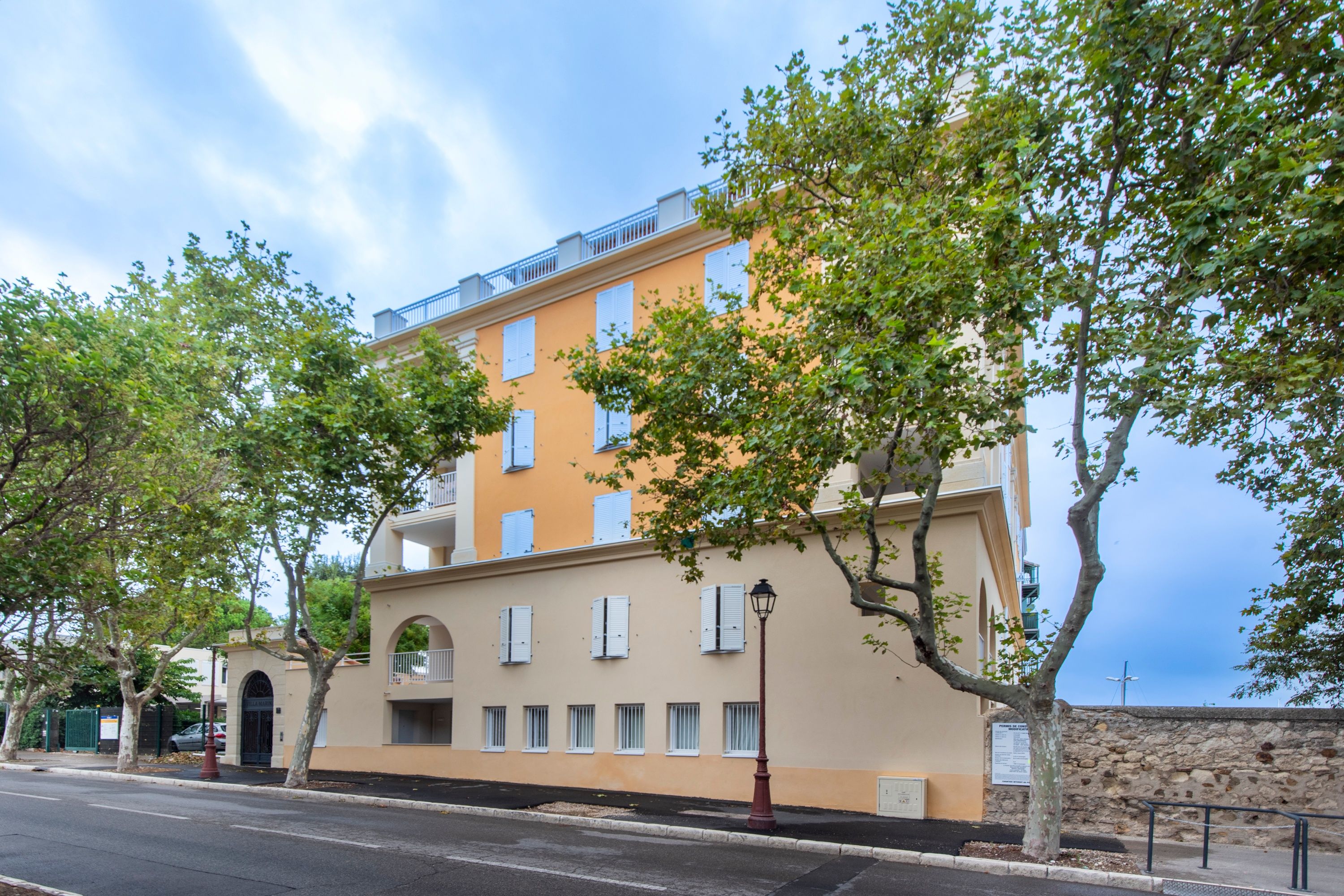 Un immeuble à plusieurs étages, doté d’une façade beige, de nombreuses fenêtres et donnant sur une rue.