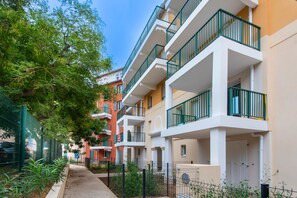 A row of multi-story residential buildings with balconies, a sidewalk, and greenery. - L’Escapade Marina - entre Camargue et Côte Bleue (Port-de-Bouc)