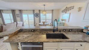 A kitchen with a granite countertop, a stainless steel sink, and a built-in dishwasher. - Spacious Beautiful Islander Beach 3009 (Fort Walton Beach)