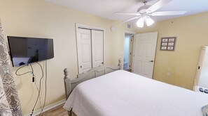 A bedroom with a bed, a ceiling fan, a television mounted on the wall, and two doors. - Spacious Beautiful Islander Beach 3009 (Fort Walton Beach)