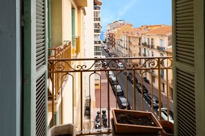A balcony with a view of a street lined with parked cars and buildings. - L'Azur Édouard VII - à 300 m des plages (Menton)