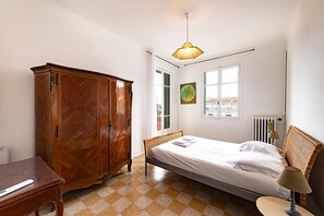 A bedroom with a bed, a wardrobe, a radiator, a window, and a hanging light fixture. - L'Azur Édouard VII - à 300 m des plages (Menton)