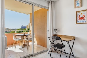 Ein Balkon mit Tisch und Stühlen, eine Schiebetür und eine Wand mit gerahmten Bildern.