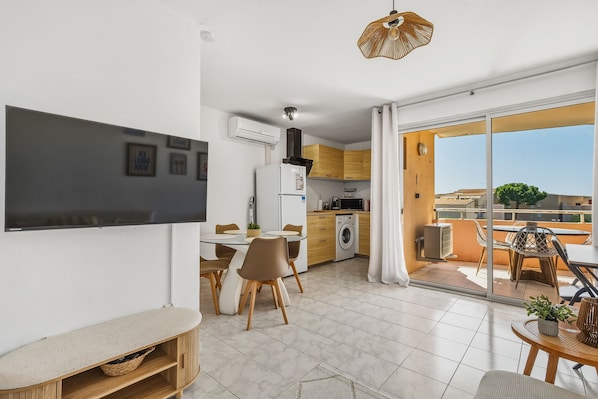 Un apartament modern amb zona de menjador, cuina i balcó.