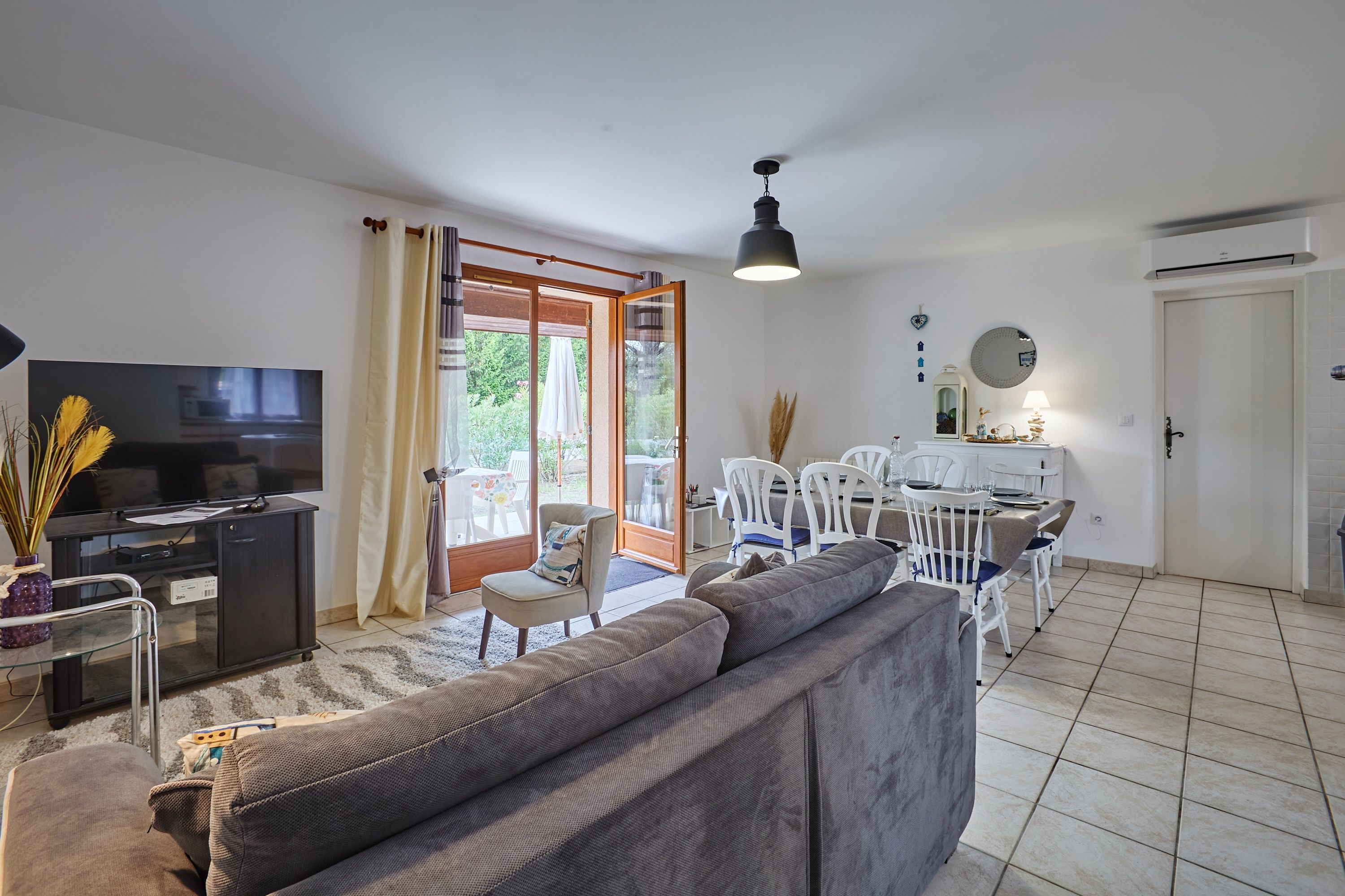 Una sala de estar con sofá, televisor y un comedor con sillas y mesa.