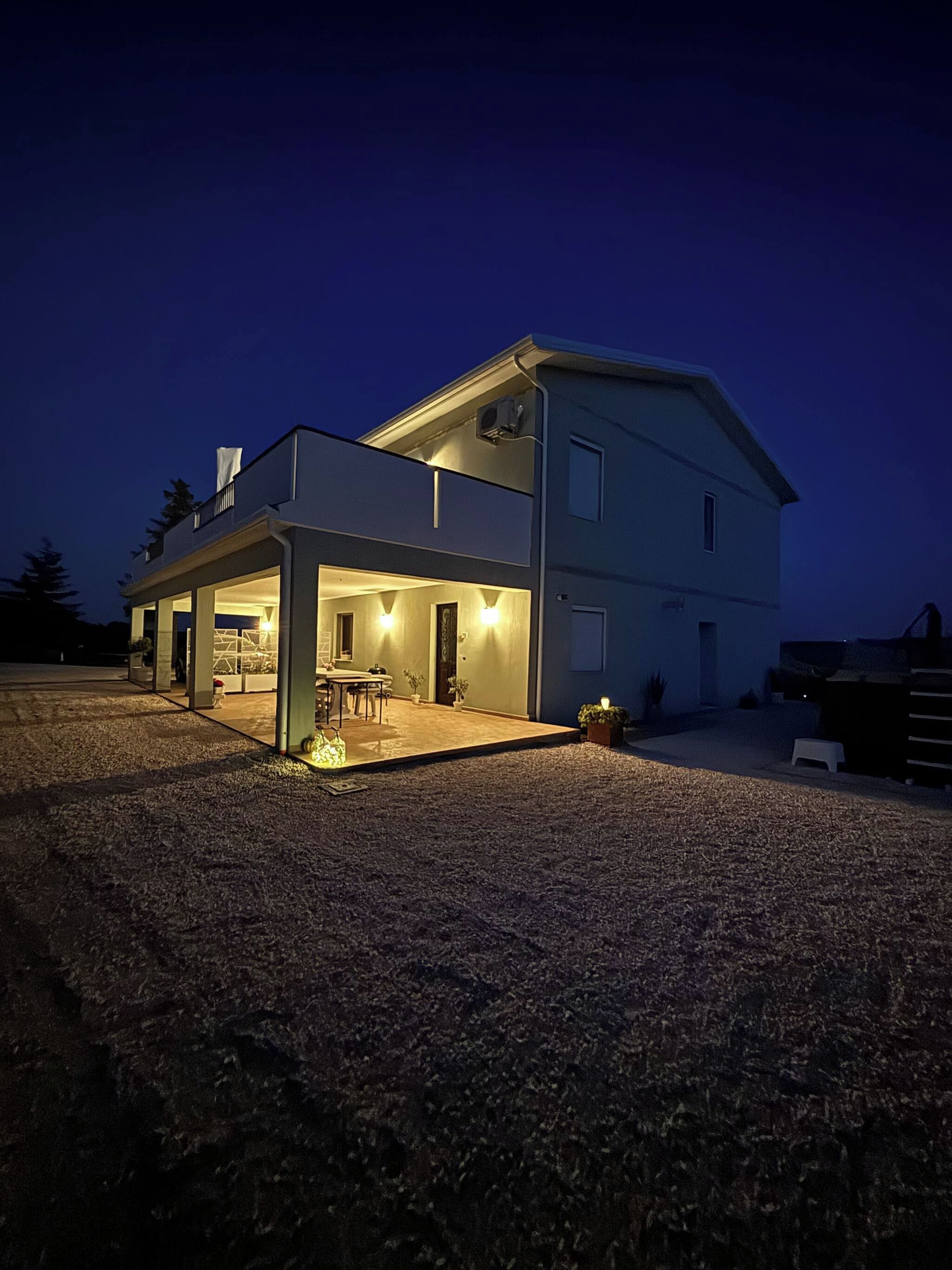 Ein zweistöckiges Haus mit einer überdachten Terrasse und einem kleinen Garten.