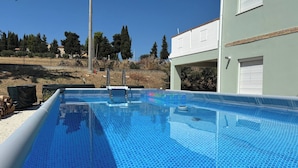 A swimming pool with a clear blue surface, surrounded by a fence and trees. - Serene Ground-floor Apartment With Private Pool in Castilenti (Castilenti)