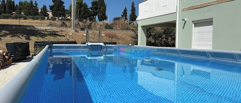 Una piscina con superficie azul cristalina, rodeada por una valla y árboles.
