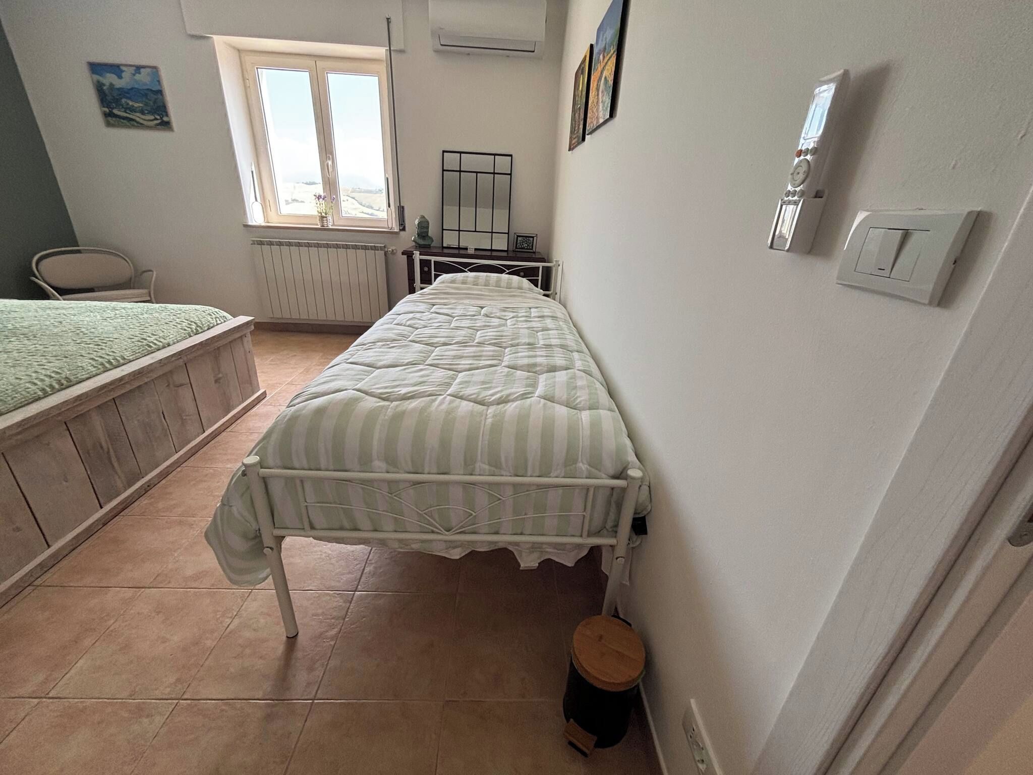 Ein Schlafzimmer mit einem Einzelbett, einem Heizkörper, einem Fenster und einem kleinen Hocker.